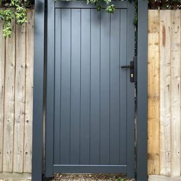 A stylish black pedestrian gate by Fence NZ, enhancing the entrance and curb appeal of an Auckland property.