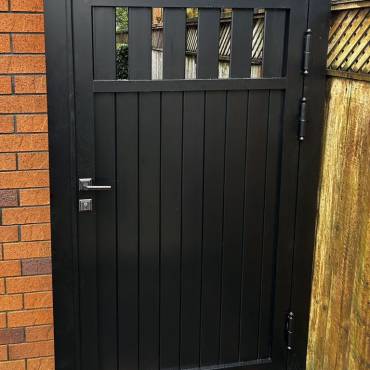 A stylish black pedestrian gate by Fence NZ, enhancing the entrance and curb appeal of an Auckland property.